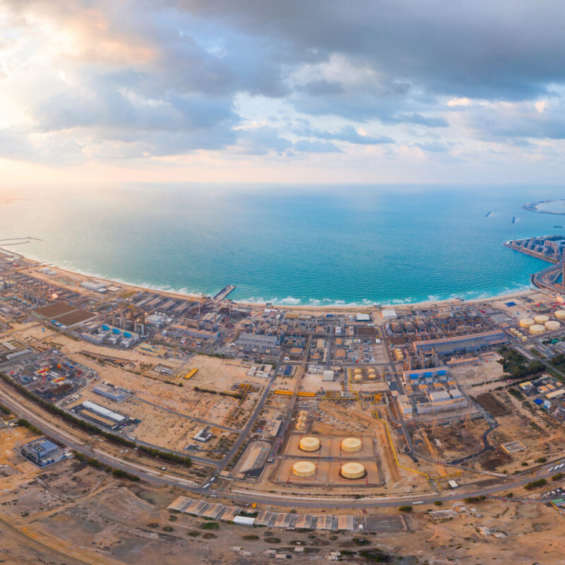 Aerial view of petrochemical oil refinery and sea in industrial engineering and energy concept in Dubai, urban city, UAE. Oil and gas tanks pipelines in industry. Modern metal factory. Power plant.
